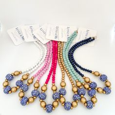 several different colored beads with gold and silver balls on each beaded strand, along with tags