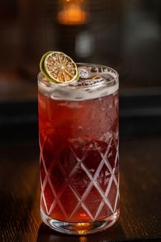 a close up of a drink on a table with a slice of lime in it