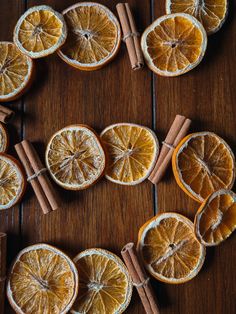 an orange cut in half with cinnamon sticks on the side next to it and several whole oranges arranged around them