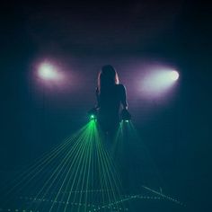 a woman standing in the dark with green lights