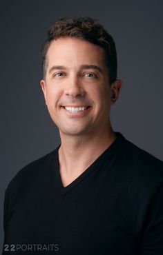 a man in black shirt smiling at the camera