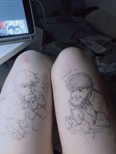 two people sitting next to each other with tattoos on their legs