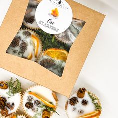 four decorated cupcakes in a box with pine cones on top and white frosting