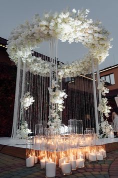 a table with candles and flowers on it in front of a large white structure at night