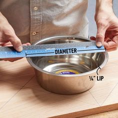 a person measuring the height of a metal bowl on a wooden surface with a tape measure