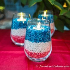 red, white and blue candles are sitting in glass vases on a tablecloth