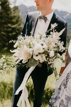 a man and woman standing next to each other in front of a field with flowers