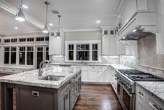 a large kitchen with white cabinets and marble counter tops