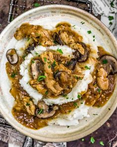 a bowl filled with mashed potatoes covered in mushrooms and gravy