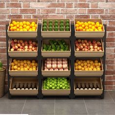 an assortment of fruits and vegetables on display in front of a brick wall with potted plants