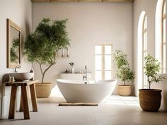 a large white bath tub sitting in a bathroom next to two sinks and potted plants