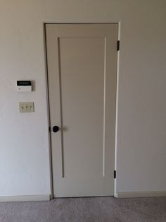 an empty room with a white door and light switch