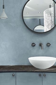 a white bowl sink sitting under a round mirror