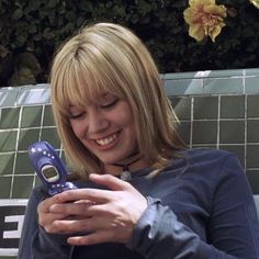 a woman smiles as she looks at her cell phone