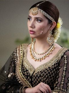 a woman in a black and gold dress with pearls on her head, wearing an elaborate necklace