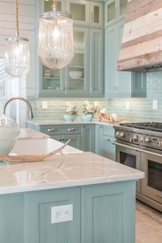 a kitchen with blue cabinets and white marble counter tops, two pendant lights hanging from the ceiling