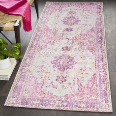 a pink, blue and yellow rug on a wooden floor next to a wicker chair