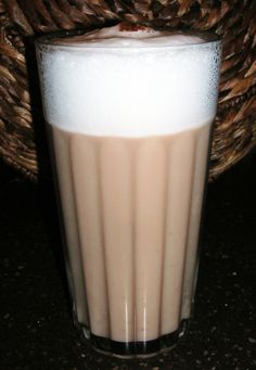 a glass filled with liquid sitting on top of a table next to a woven basket