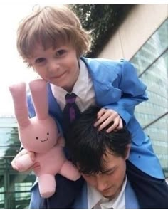 a young boy is being held up by an older man in a suit and tie