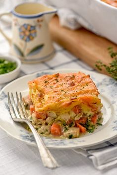 a white plate topped with food next to a bowl of peas and carrots on a table