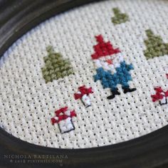 a close up of a cross stitch pattern on a white cloth with a black frame