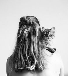 a woman with long hair and a cat on her back