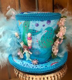 This is a great hat for a tea party or beach theme get together .  This Tea Party Hat is a medium  size.  Measures approx. 6"  and 4.5" tall plus decorations  Has blue & turquoise feathers. It has 2 hat pins. Mermaid tail pick and mermaid  pick on hat.  Hat has white elastic to hold on your head. Elastic goes over your head behind ears &  under your hair. Also included is 2 clips to help stay on if needed. Whimsical High Crown Hats For Costume Party, Whimsical Hats For Carnival Themed Events, Whimsical High Crown Hat For Themed Events, Fun Summer Hats For Costume Party, Themed Curved Brim Hats For Costume Party, Themed Hats With Curved Brim For Costume Party, Handmade High Crown Top Hat For Party, Themed Mini Hats With Curved Brim For Party, Handmade Themed Costume Hats And Headpieces For Themed Events