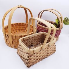 three wicker baskets sitting next to each other on a white surface with plants in them