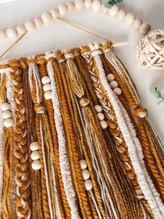 a close up of a string and wood bead wall hanging on a white surface