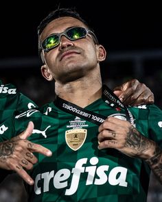 two soccer players with their arms around each other, one is wearing sunglasses and the other has tattoos on his arm