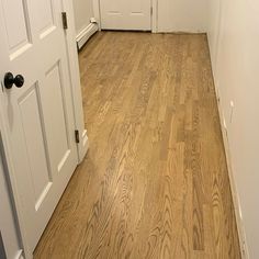 an empty hallway with white doors and wood floors