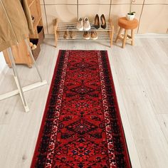 a long red rug is on the floor in front of a coat rack with shoes