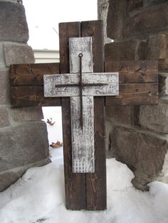 a wooden cross sitting on top of snow covered ground