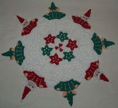 a crocheted christmas decoration with santa hats and holly wreaths on the center