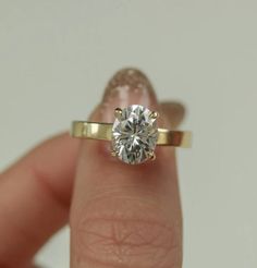 a woman's hand holding a ring with a diamond in the middle and a gold band around it