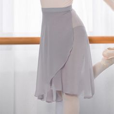 a ballerina is practicing her moves in the ballet studio, wearing a white top and grey skirt