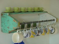 there are cups and mugs hanging on the rack