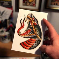 a hand holding up a card with an image of a snake on it's side