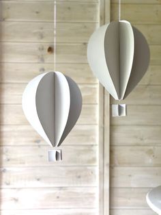 two paper hot air balloons hanging from strings in front of a wooden paneled wall