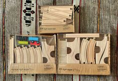 three wooden toy train sets in boxes on a carpeted surface with other wood toys