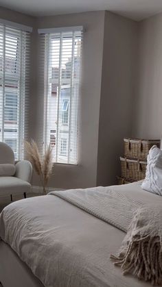 a white bed sitting in a bedroom next to two windows with shutters on them