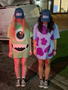 two girls in costumes standing next to each other on the street at night with cars behind them