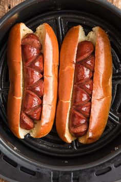 two hot dogs in buns on top of an air fryer