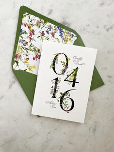 a card with the number four and floral design on it, sitting next to an envelope