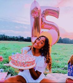 a woman sitting on the ground with a cake in front of her