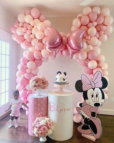 a minnie mouse balloon arch is decorated with balloons and other decorations for a birthday party