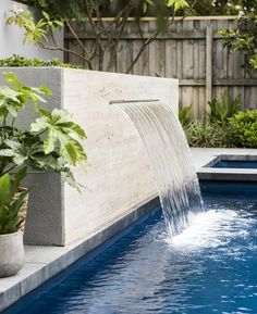 an outdoor pool with water flowing from it's sides and plants growing on the side