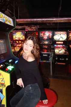 a woman sitting on top of a red stool in front of a video game machine