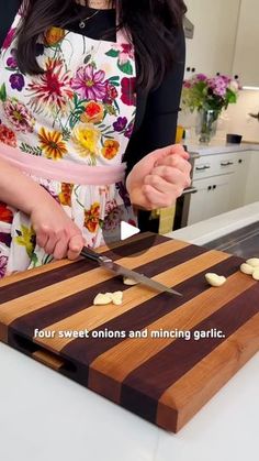 a woman cutting up food on top of a wooden cutting board next to a knife