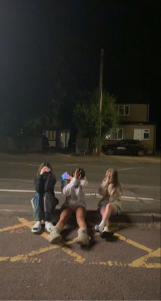 four people sitting in the middle of a parking lot with their arms around each other